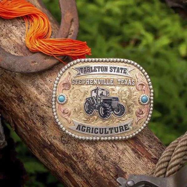 A custom farming belt buckle for Tartleton State, Stephenville, Texas, featuring a tractor figure on a golden jeweler's bronze hand engraved base